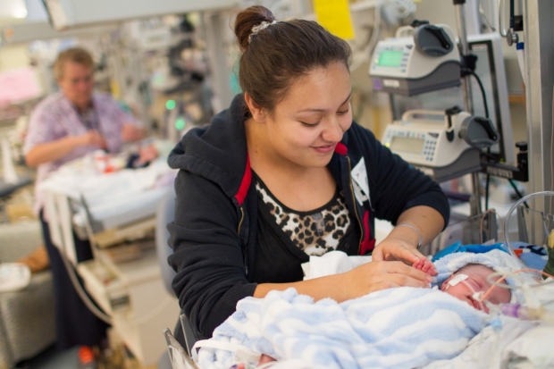 Mother standing at her baby's bedside in the NICU