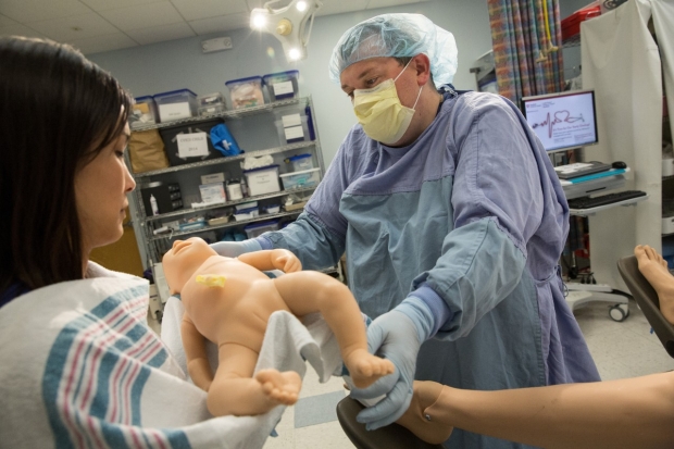 Infant Resucitation Simulation - Doctor hands Dr. Nicole Yamada an infant dummy in a delivery/resusciataion simluation.