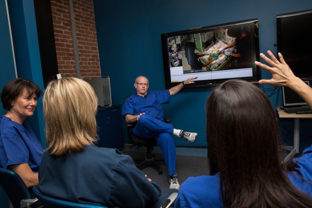 Simulation Debrief at CAPE - Dr. Louis Halamek answers questions while pointing at a screen displaying a recording of the simulation under discussion.